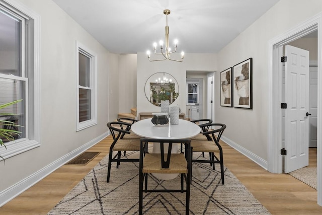 dining area with light hardwood / wood-style flooring and an inviting chandelier