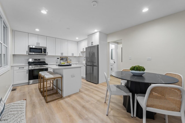 kitchen with a center island, a kitchen bar, white cabinetry, and stainless steel appliances