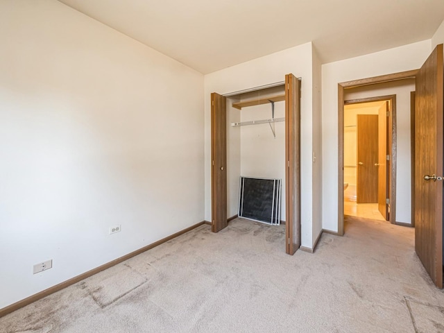 unfurnished bedroom with light carpet and a closet