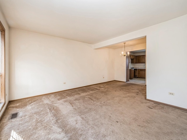 unfurnished room with carpet floors and a chandelier