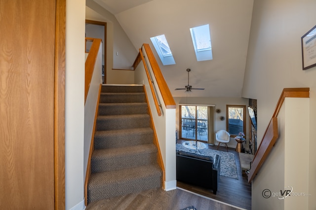 staircase featuring ceiling fan, vaulted ceiling with skylight, and hardwood / wood-style floors