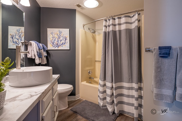 full bathroom with a textured ceiling, shower / bathtub combination with curtain, wood-type flooring, vanity, and toilet