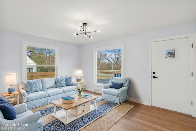 living room with a notable chandelier, plenty of natural light, and light hardwood / wood-style flooring