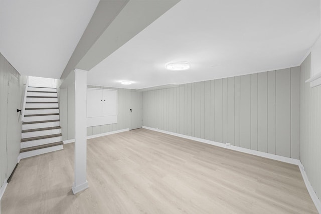 basement with light wood-type flooring and wooden walls