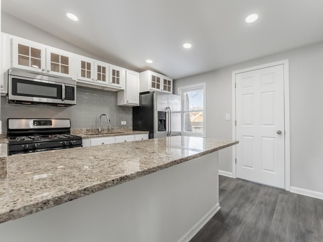 kitchen featuring light stone countertops, appliances with stainless steel finishes, sink, dark hardwood / wood-style floors, and white cabinetry