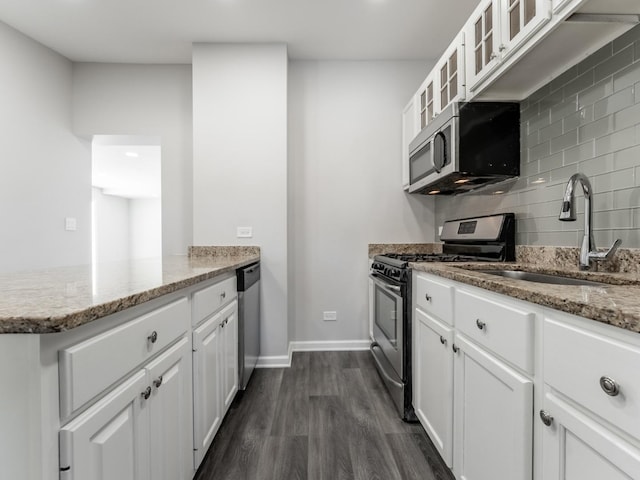 kitchen with light stone countertops, sink, backsplash, white cabinets, and appliances with stainless steel finishes