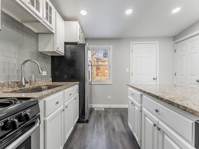 kitchen with tasteful backsplash, white cabinetry, sink, and light stone counters