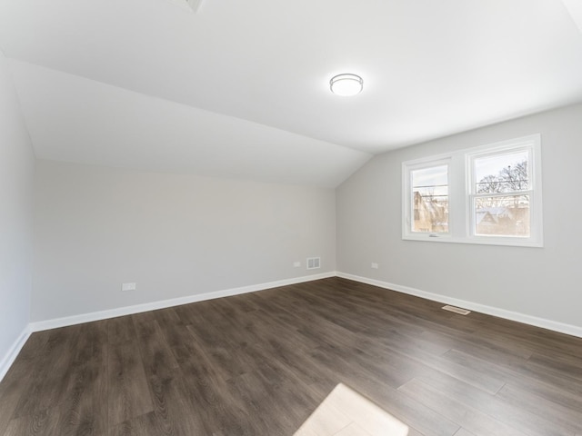 bonus room with vaulted ceiling and dark wood-type flooring