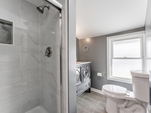 bathroom with plenty of natural light, a shower with shower door, and toilet