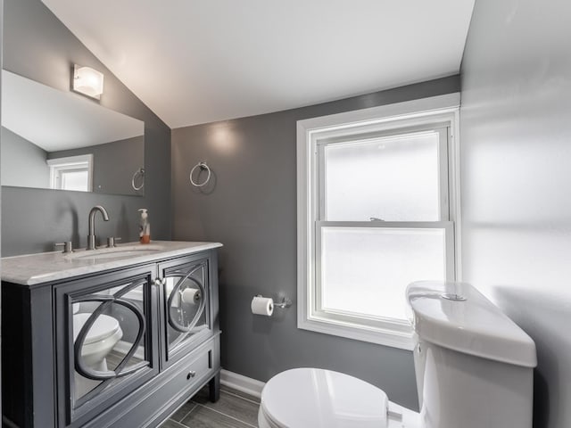 bathroom featuring vanity, lofted ceiling, and toilet