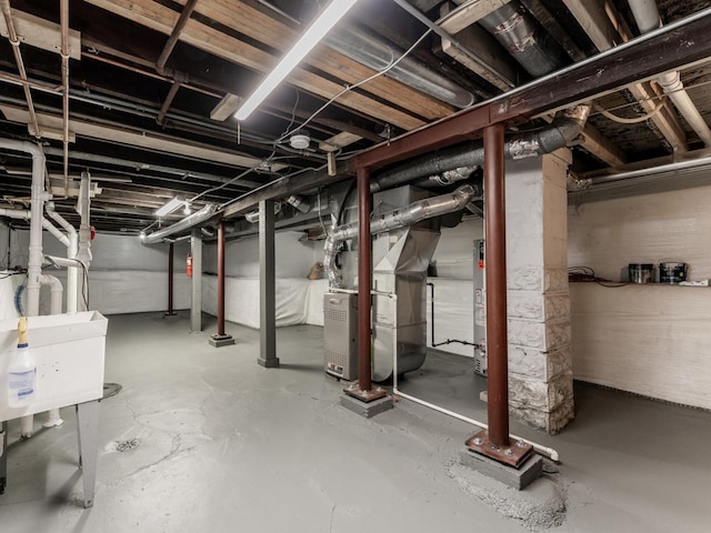 basement featuring heating unit, sink, and gas water heater