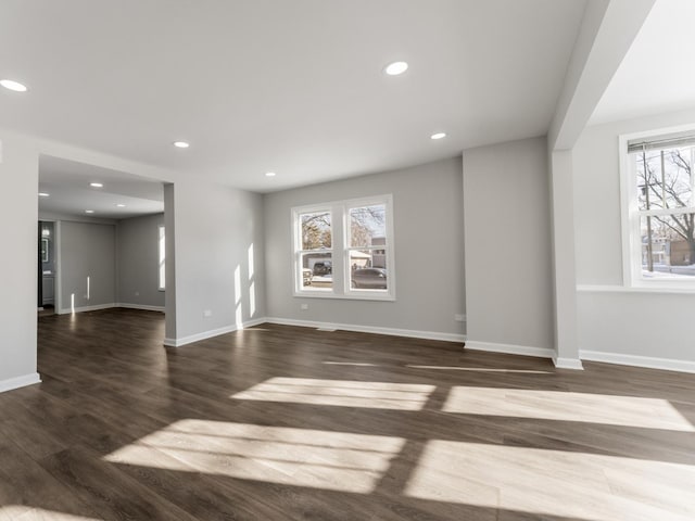 unfurnished living room featuring dark wood-type flooring and a healthy amount of sunlight