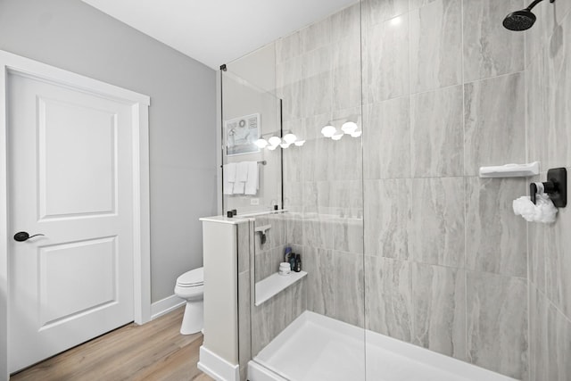 bathroom featuring toilet, wood-type flooring, and tiled shower