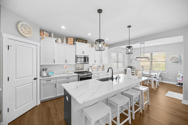 kitchen with appliances with stainless steel finishes, an island with sink, white cabinetry, and sink