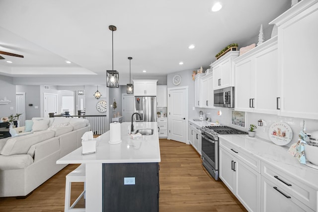 kitchen with appliances with stainless steel finishes, decorative light fixtures, a kitchen breakfast bar, a kitchen island with sink, and sink