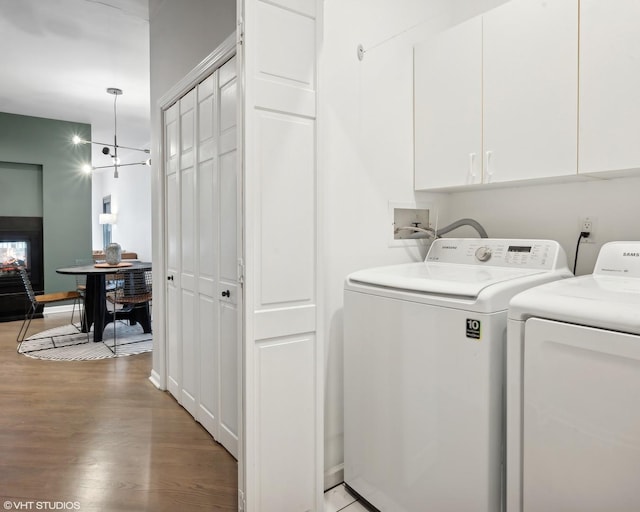 laundry room featuring washing machine and clothes dryer, cabinets, and wood-type flooring