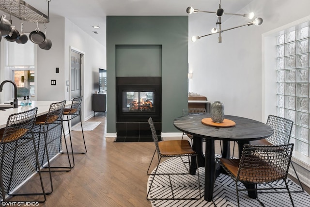 dining area featuring a multi sided fireplace, light wood-type flooring, and a chandelier