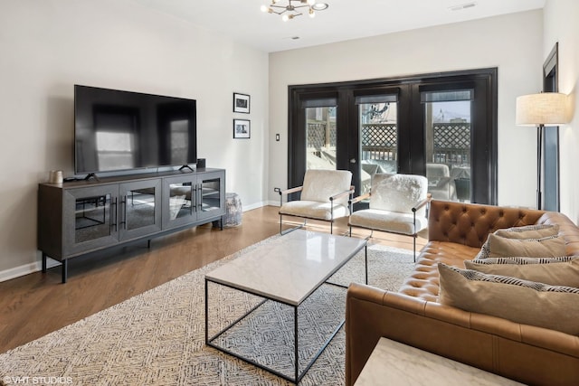 living room featuring hardwood / wood-style floors, a chandelier, and french doors