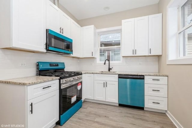 kitchen featuring dishwasher, sink, white cabinets, and gas range oven