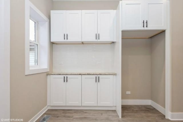 kitchen with white cabinets, light hardwood / wood-style floors, and light stone countertops