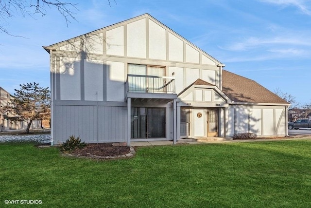 back of house featuring a balcony and a lawn