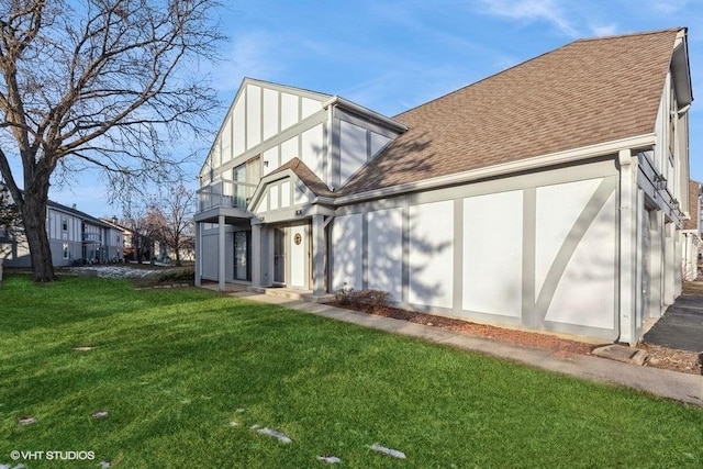 rear view of house featuring a balcony and a lawn