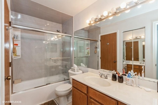 full bathroom featuring vanity, shower / bath combination with glass door, and toilet