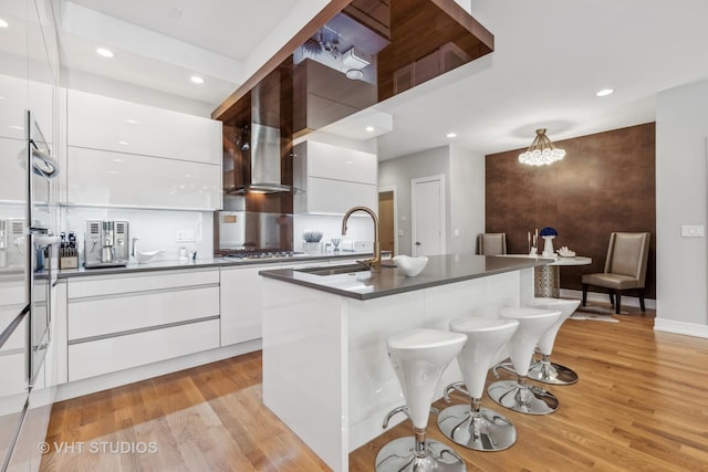 kitchen with sink, a kitchen breakfast bar, white cabinets, and a center island with sink