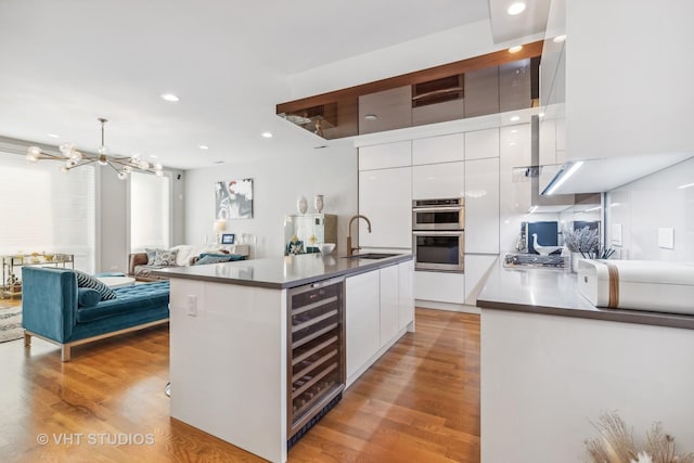 kitchen with light hardwood / wood-style floors, wine cooler, white cabinets, and sink