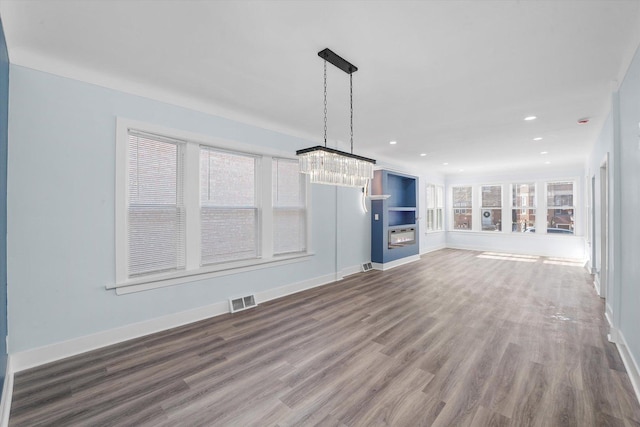 unfurnished living room featuring hardwood / wood-style floors and an inviting chandelier