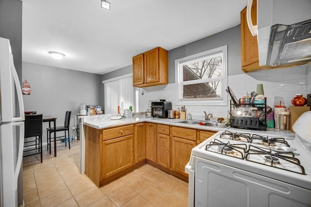 kitchen with kitchen peninsula, backsplash, white appliances, sink, and light tile patterned flooring