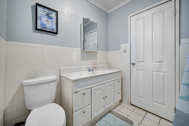 bathroom featuring tile patterned floors, vanity, crown molding, tile walls, and toilet