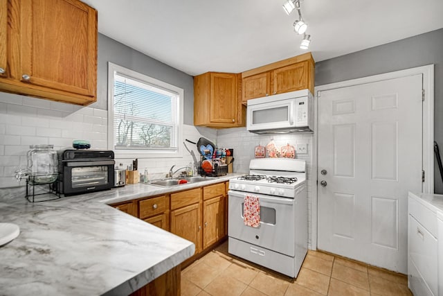 kitchen featuring decorative backsplash, white appliances, sink, and light tile patterned floors