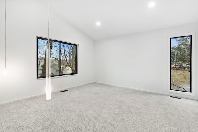 carpeted spare room with vaulted ceiling