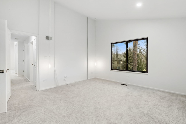 carpeted empty room featuring high vaulted ceiling