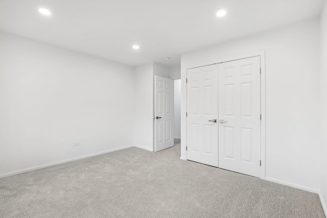 unfurnished bedroom featuring light colored carpet and a closet