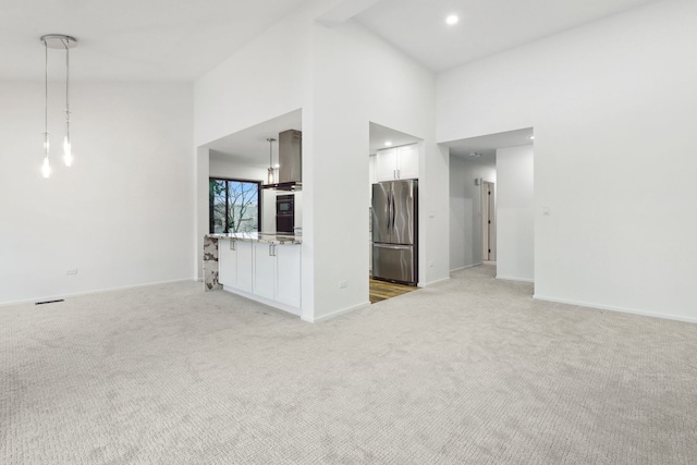 unfurnished living room featuring carpet floors and a high ceiling