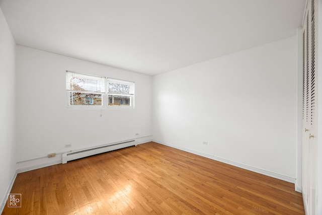 empty room with a baseboard radiator and hardwood / wood-style flooring