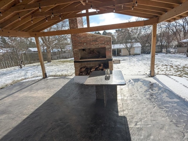 snow covered patio featuring an outdoor brick fireplace