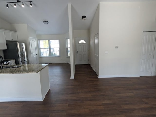 kitchen with stainless steel fridge, light stone counters, dark wood-type flooring, sink, and white cabinets