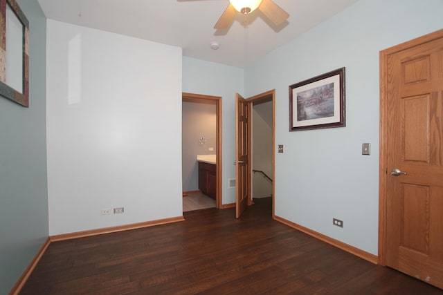 unfurnished bedroom with ensuite bathroom, ceiling fan, and dark wood-type flooring