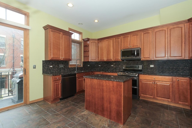 kitchen featuring tasteful backsplash, stainless steel appliances, sink, dark stone countertops, and a center island