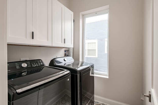 clothes washing area with washing machine and dryer and cabinets