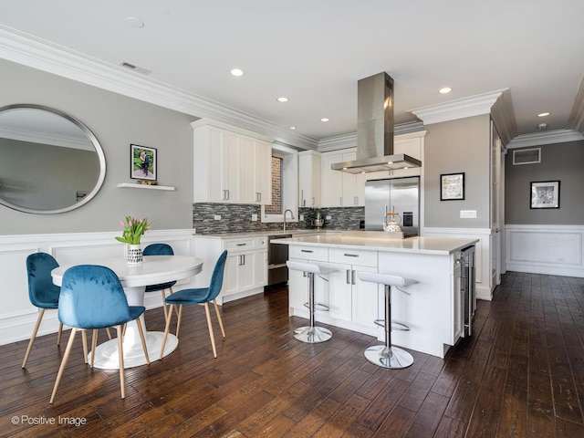 kitchen with island range hood, a kitchen island, white cabinets, light countertops, and appliances with stainless steel finishes