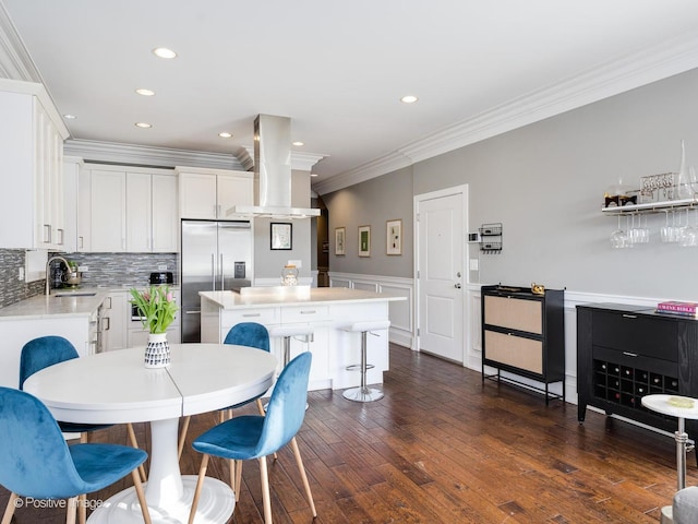 kitchen with light countertops, built in refrigerator, a kitchen island, and white cabinetry