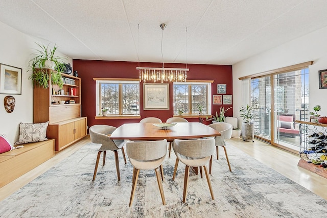 dining area with an inviting chandelier, a textured ceiling, and hardwood / wood-style flooring