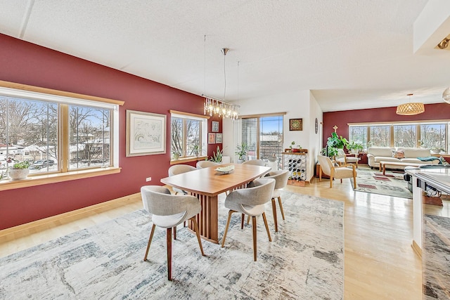 dining space with a textured ceiling, an inviting chandelier, and light hardwood / wood-style floors