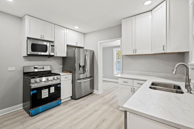 kitchen featuring white cabinets, light hardwood / wood-style floors, sink, and appliances with stainless steel finishes