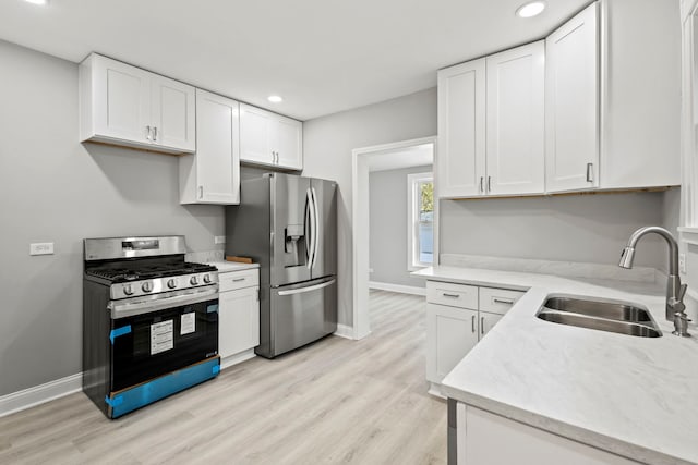 kitchen with sink, white cabinetry, stainless steel appliances, and light hardwood / wood-style flooring