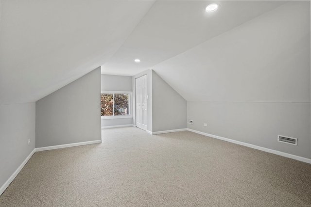 additional living space featuring light colored carpet and lofted ceiling